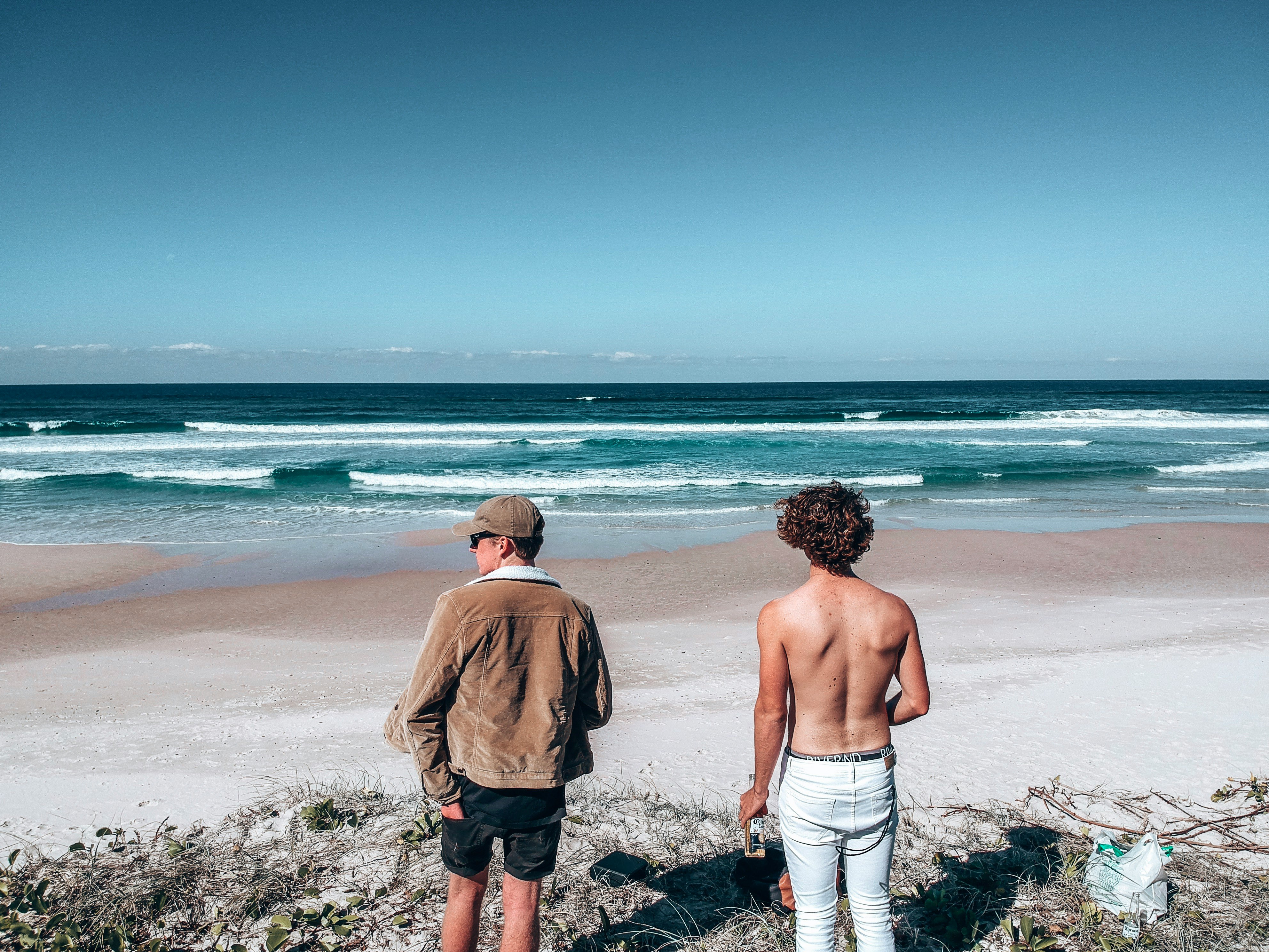 2 men standing on beach during daytime